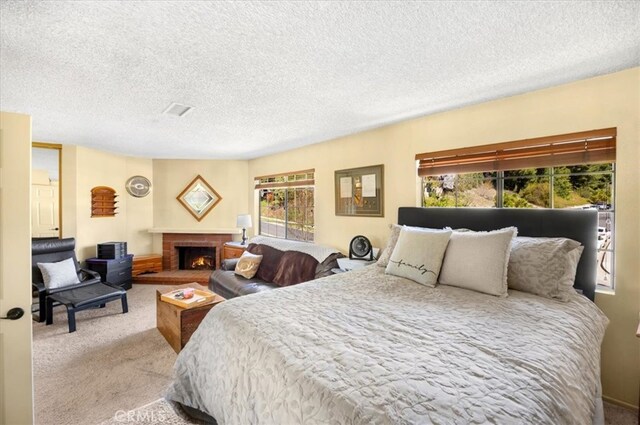 carpeted bedroom with multiple windows, a brick fireplace, and a textured ceiling