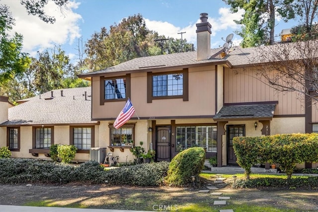 townhome / multi-family property with cooling unit, roof with shingles, and a chimney