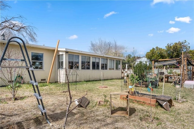 rear view of property with crawl space, a lawn, and a vegetable garden