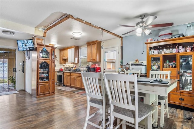 kitchen with stainless steel gas range oven, visible vents, dark wood-style floors, and ceiling fan