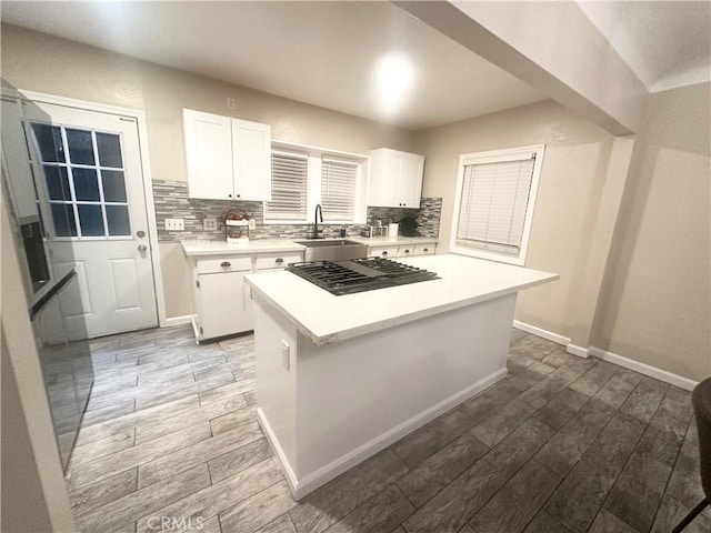 kitchen featuring a sink, backsplash, white cabinets, and light countertops