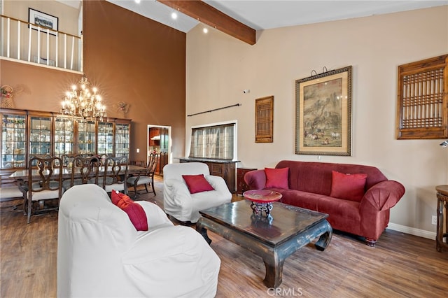 living area with beamed ceiling, high vaulted ceiling, wood finished floors, an inviting chandelier, and baseboards