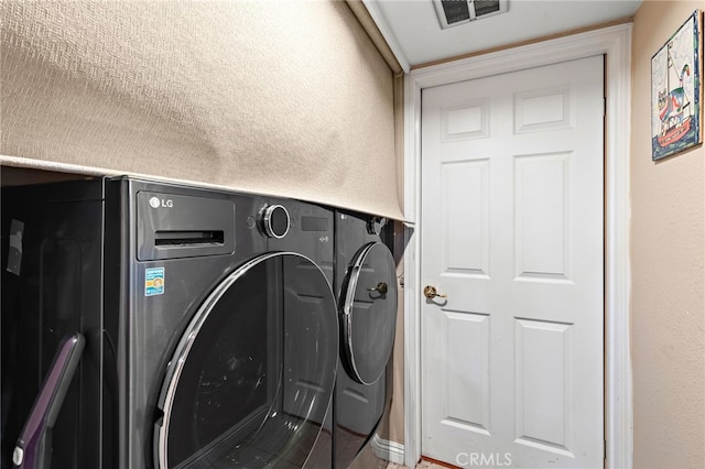 laundry room with laundry area, a textured wall, visible vents, and washing machine and clothes dryer