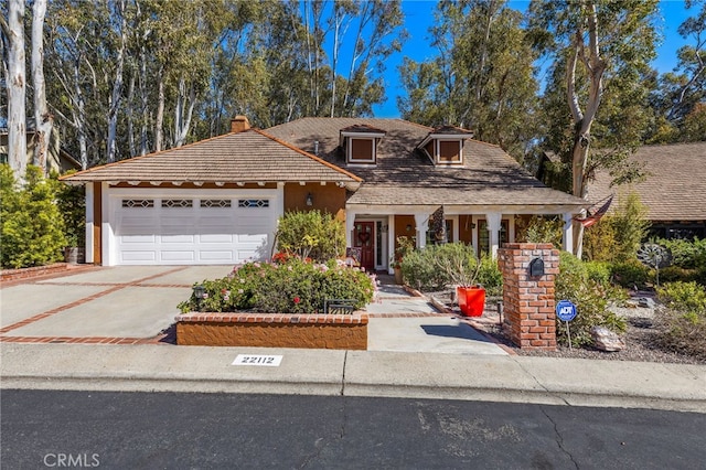 view of front of property with concrete driveway, an attached garage, a chimney, and stucco siding