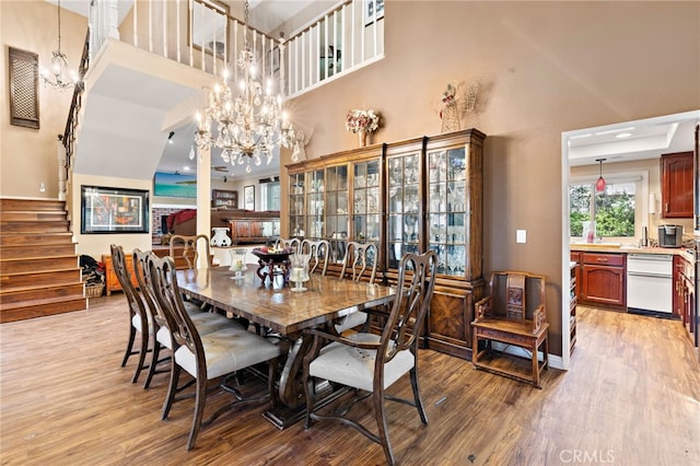 dining room with stairway, light wood-type flooring, and an inviting chandelier