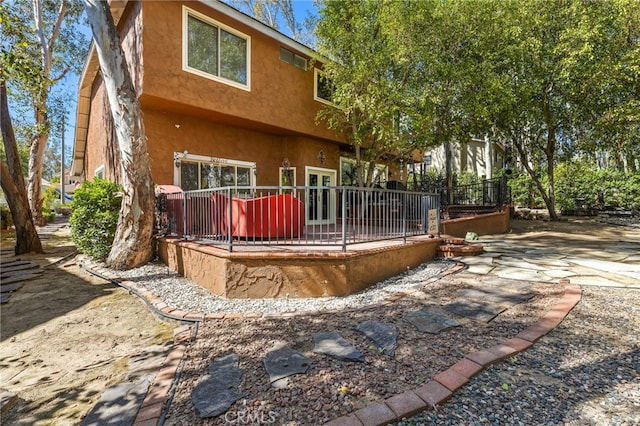 back of house with a wooden deck and stucco siding