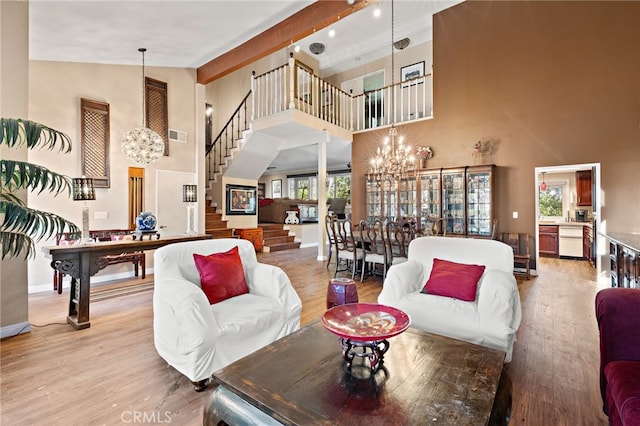 living room with light wood finished floors, a notable chandelier, stairs, and beam ceiling