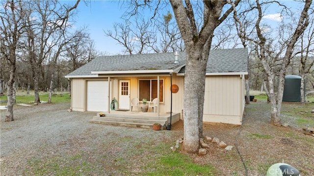 view of front of house featuring a garage, covered porch, and roof with shingles