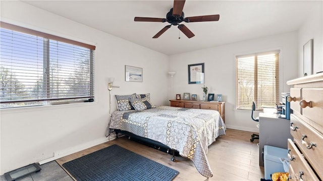 bedroom featuring light wood-style flooring, a ceiling fan, and baseboards