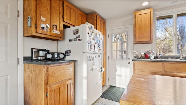 kitchen with a wealth of natural light, brown cabinets, freestanding refrigerator, and light tile patterned flooring