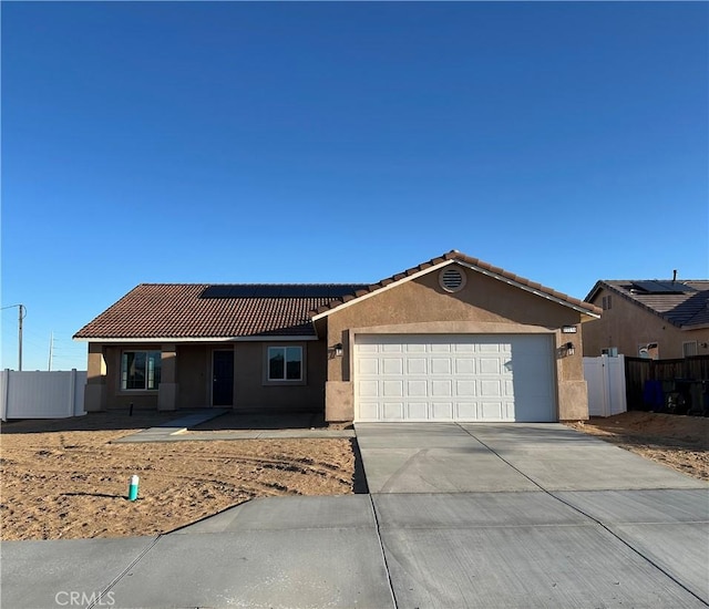 ranch-style house featuring fence, concrete driveway, roof mounted solar panels, stucco siding, and a garage