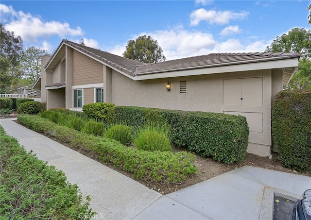 view of side of property featuring stucco siding and a tiled roof