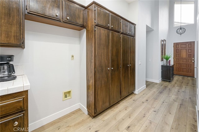 kitchen with tile countertops, baseboards, a high ceiling, light wood-style flooring, and dark brown cabinetry