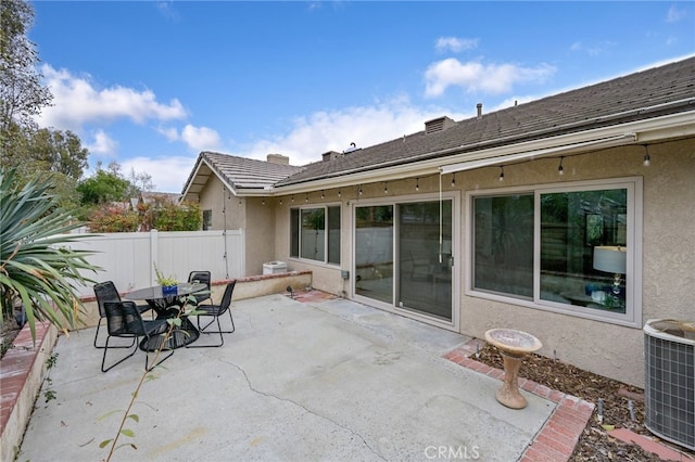 view of patio featuring outdoor dining area, central AC unit, and fence