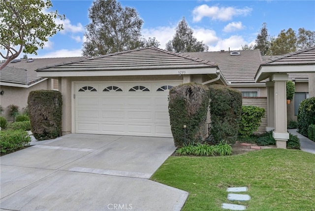 ranch-style home featuring stucco siding, a front lawn, driveway, a garage, and a tiled roof