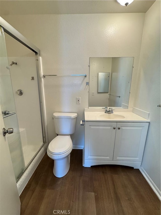 full bathroom featuring toilet, wood finished floors, a shower stall, baseboards, and vanity