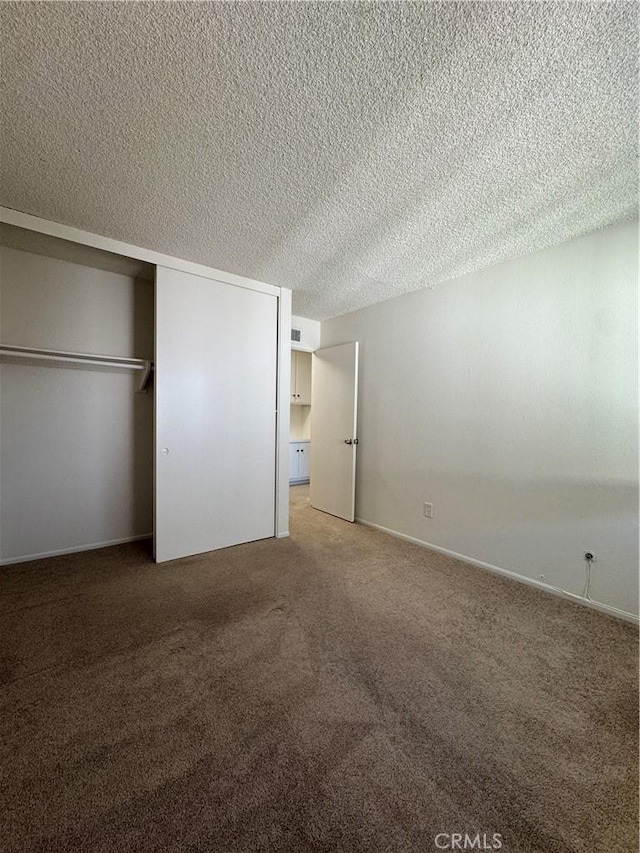 unfurnished bedroom featuring a closet, visible vents, a textured ceiling, and carpet