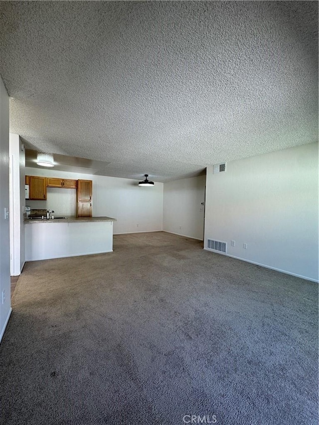 unfurnished living room with a textured ceiling, carpet flooring, visible vents, and ceiling fan