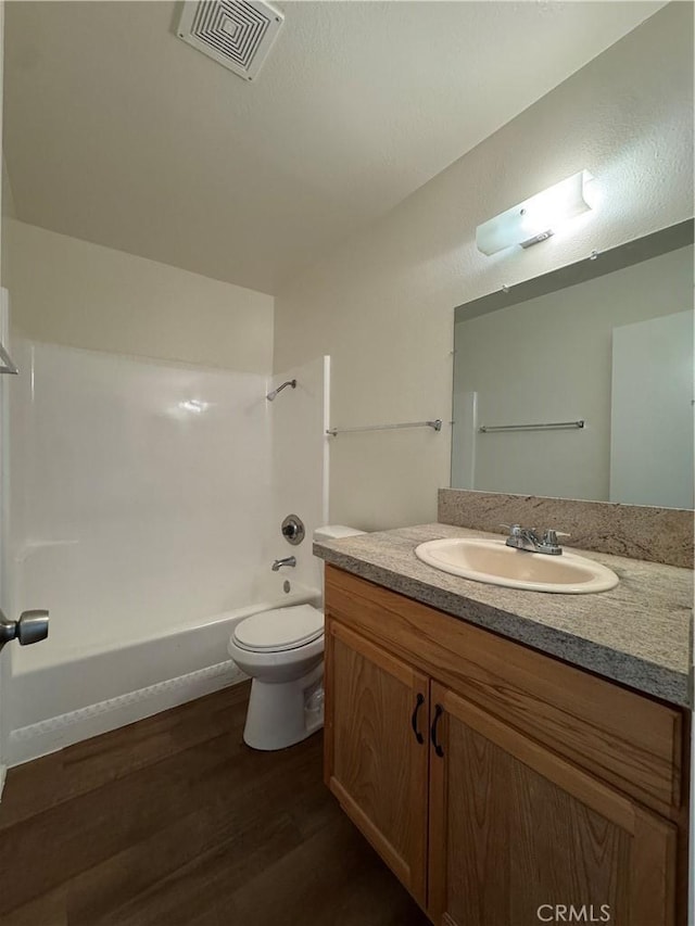 full bath featuring visible vents, tub / shower combination, toilet, wood finished floors, and vanity