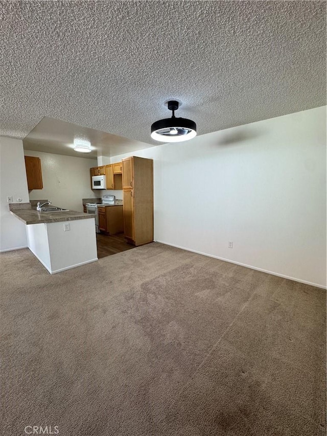 kitchen featuring white appliances, a peninsula, a textured ceiling, open floor plan, and dark carpet