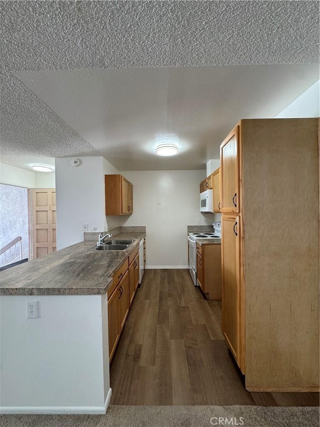 kitchen with dark wood-type flooring, a sink, white appliances, a peninsula, and baseboards