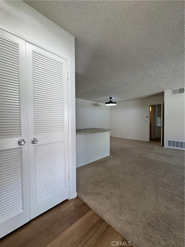 corridor featuring carpet flooring, visible vents, and a textured ceiling