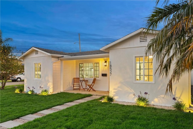 back of house with a lawn and stucco siding