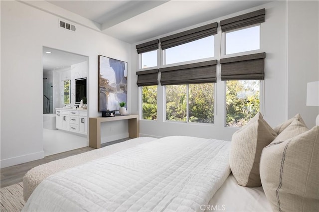 bedroom featuring visible vents, multiple windows, baseboards, and wood finished floors