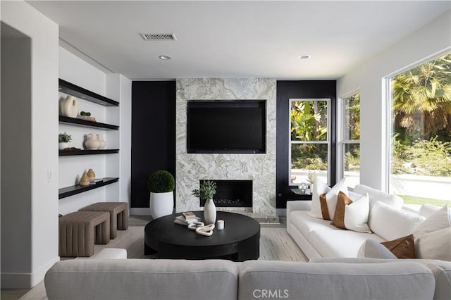 living area featuring built in features, visible vents, wood finished floors, and a premium fireplace