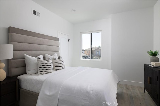 bedroom featuring visible vents, baseboards, and wood finished floors