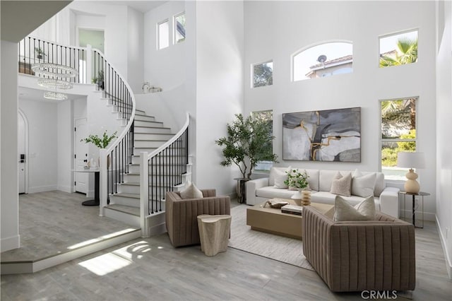 living room featuring a chandelier, a healthy amount of sunlight, stairs, and wood finished floors