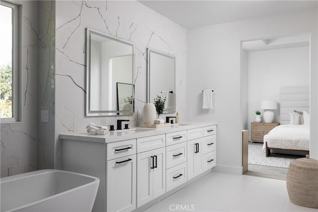 ensuite bathroom featuring a freestanding bath, double vanity, ensuite bath, and a sink