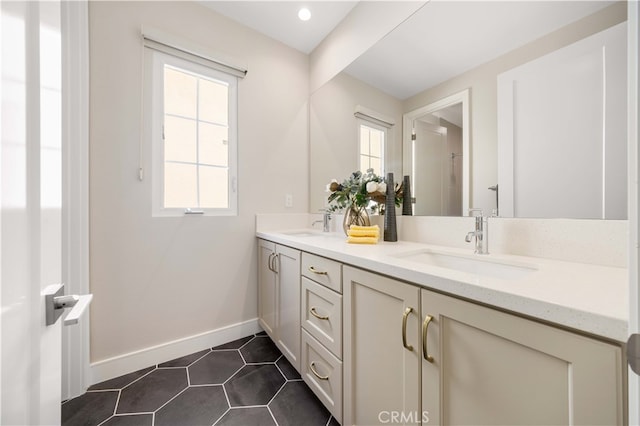 full bathroom with double vanity, baseboards, tile patterned floors, and a sink