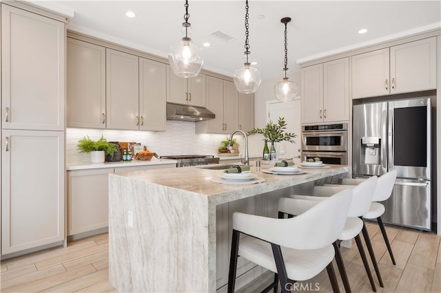 kitchen featuring visible vents, a sink, decorative backsplash, under cabinet range hood, and appliances with stainless steel finishes