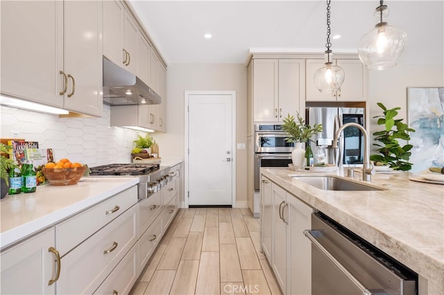 kitchen featuring under cabinet range hood, stainless steel appliances, light countertops, and a sink