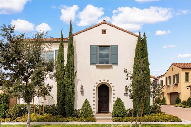 mediterranean / spanish-style house featuring stucco siding, driveway, and a tile roof