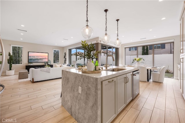 kitchen featuring a sink, light stone counters, recessed lighting, wood tiled floor, and hanging light fixtures