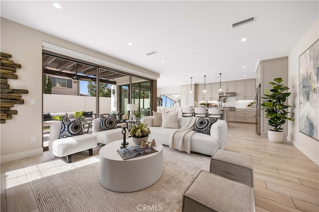 living room with recessed lighting, light wood-type flooring, baseboards, and visible vents