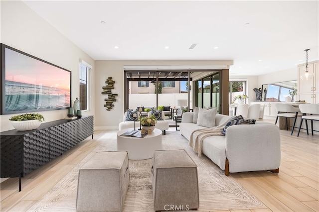 living area featuring recessed lighting, baseboards, and light wood-style flooring