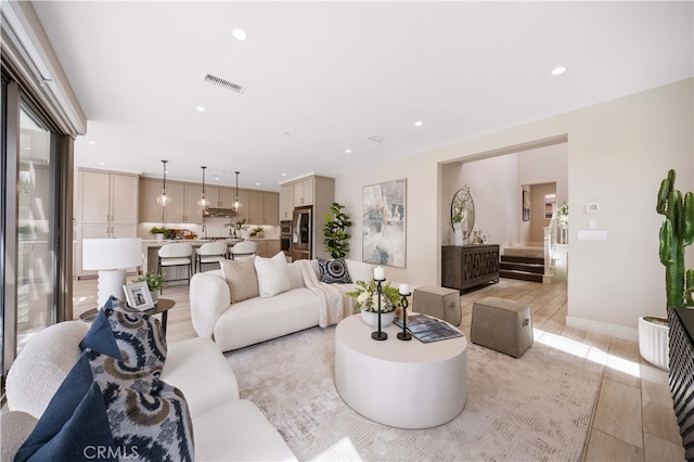 living area featuring stairway, baseboards, visible vents, light wood-style flooring, and recessed lighting