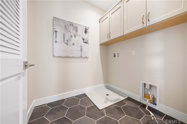 laundry room featuring hookup for a washing machine, dark tile patterned floors, cabinet space, and baseboards