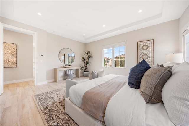 bedroom featuring a tray ceiling, light wood-style flooring, recessed lighting, and baseboards