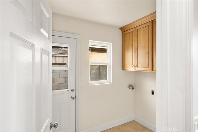 clothes washing area featuring light tile patterned flooring, cabinet space, electric dryer hookup, and baseboards