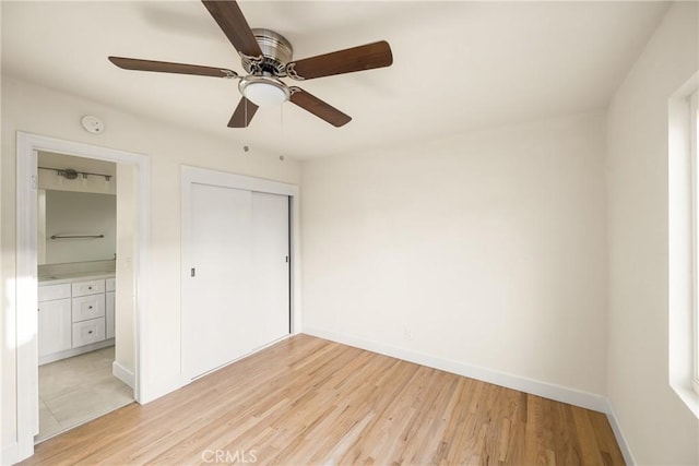 unfurnished bedroom with baseboards, light wood finished floors, ceiling fan, a closet, and ensuite bathroom