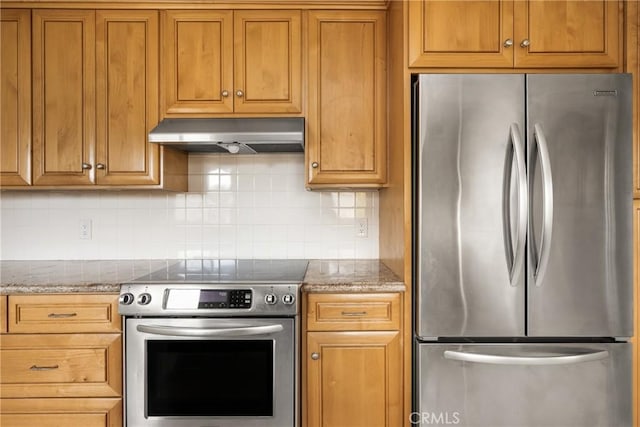 kitchen featuring tasteful backsplash, under cabinet range hood, brown cabinetry, stone countertops, and stainless steel appliances