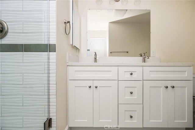 full bath with double vanity, a shower with door, and a sink