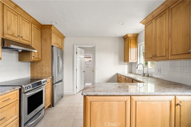 kitchen with light tile patterned floors, a peninsula, a sink, under cabinet range hood, and appliances with stainless steel finishes