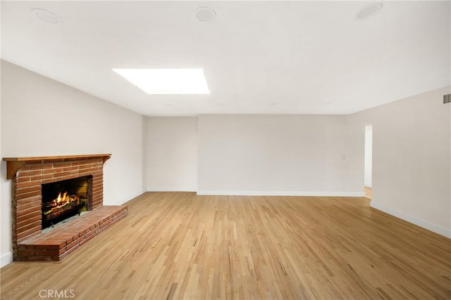 unfurnished living room featuring a fireplace, baseboards, and light wood-style floors