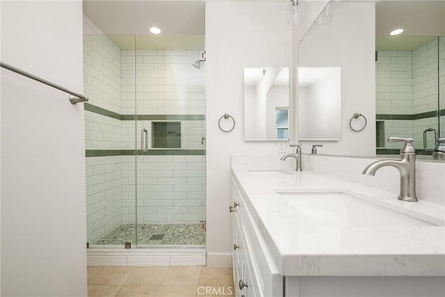 full bathroom featuring tile patterned floors, a stall shower, double vanity, and a sink