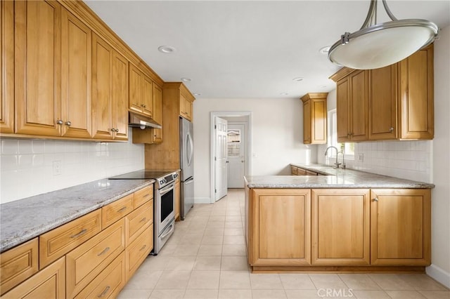 kitchen with under cabinet range hood, light stone counters, a sink, stainless steel appliances, and a peninsula